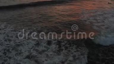 日落时飞越冲浪者冲浪海浪。 令人惊叹的日落空中海景。 有质感的海洋的自上而下拍摄